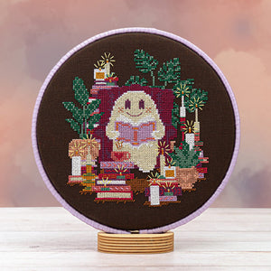 Cross-stitched design of a ghost with books