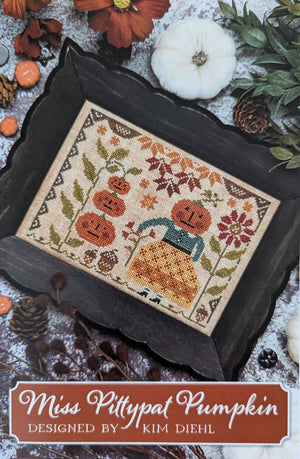 A cross-stitch design titled "Miss Pittypat Pumpkin" by Kim Diehl of Its Sew Emma includes pumpkins, flowers, pinecones, and leaves.